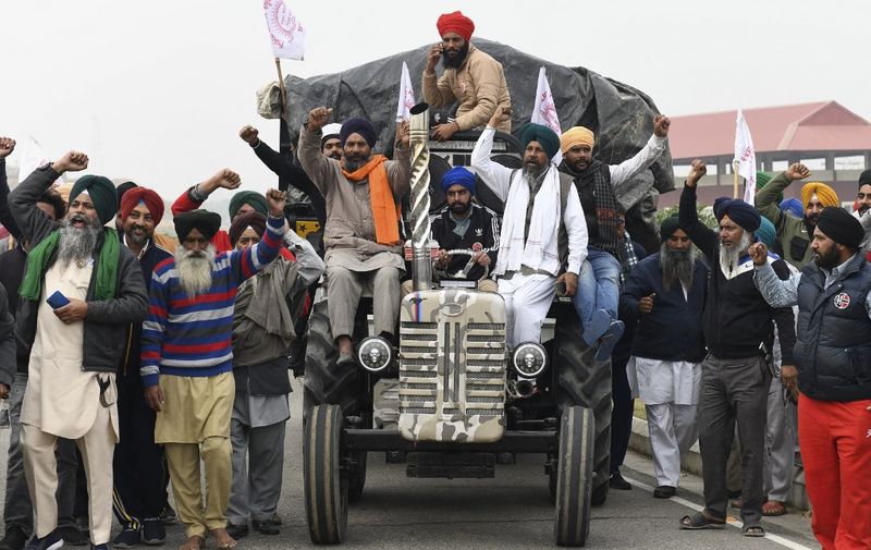 Farmers shout slogans as they make their way along the road to Delhi to join farmers who are continuing their protest against the central government's agricultural reforms, in Beas some 55 km from Amritsar on December 5, 2021. (Photo by NARINDER NANU / AFP)