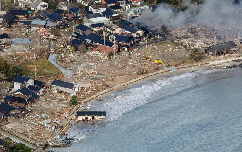 This aerial photo provided by Jiji Press shows smoke rising from a house fire (top R) along with other damage along the coast in the town of Noto, Ishikawa prefecture on January 2, 2024, a day after a major 7.5 magnitude earthquake struck the Noto region in Ishikawa prefecture. Japanese rescuers battled against the clock and powerful aftershocks on January 2 to find survivors of a major earthquake that struck on New Year's Day, killing at least 30 people and causing widespread destruction. (Photo by JIJI PRESS / AFP) / Japan OUT