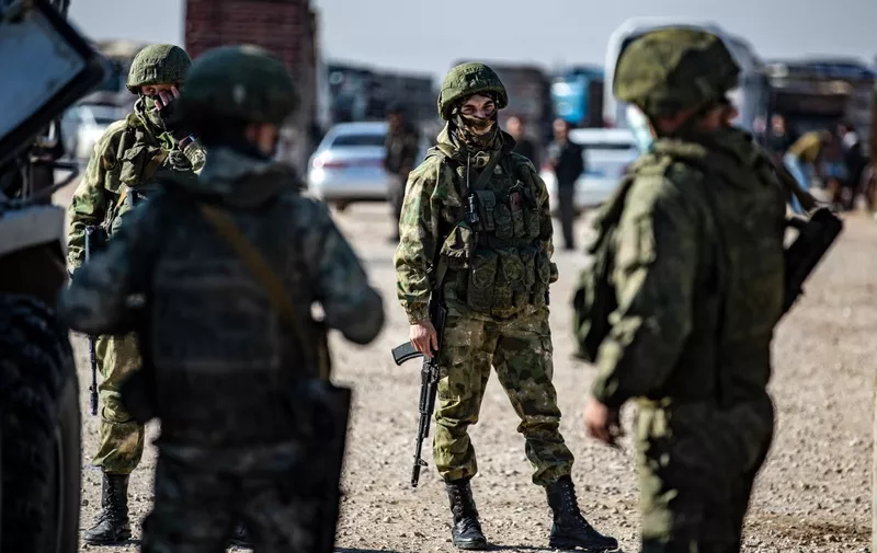 Russian soldiers gather as troops escort a convoy of Syrian civilians leaving the town of Tal Tamr in the northeastern Hasakeh province, to return to their homes in the northern town of Ain Issa in the countryside of the Raqqa region, via the strategic M4 highway, on January 10, 2021. - The town of Tal Tamr is on the front line between the Syrian Democratic Forces (SDF) and the Syrian factions supported by Turkey. 
Civilians stranded on both sides of the line because of heavy fighting, have been able to return to their homes during the past few days. (Photo by Delil SOULEIMAN / AFP)