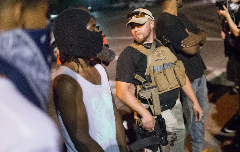 FERGUSON, MO - AUGUST 10: An Oath Keeper, carrying a rifle, walks along West Florrisant Street as demonstrators, marking the first anniversary of the shooting of Michael Brown, protest on August 10, 2015 in Ferguson, Missouri. Brown was shot and killed by a Ferguson police officer on August 9, 2014. His death sparked months of sometimes violent protests in Ferguson and drew nationwide focus on police treatment of black offenders.   Scott Olson/Getty Images/AFP