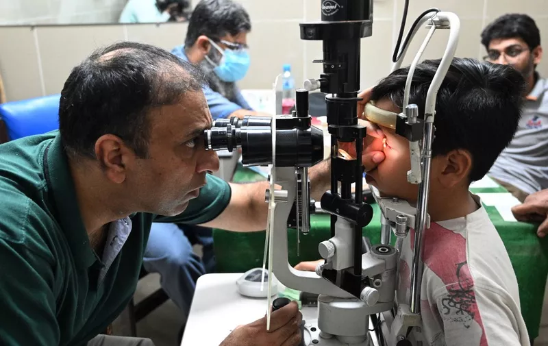 A doctor examines a boy suffering from an eye infection at a hospital in Rawalpindi on September 28, 2023. More than 56,000 Pakistan schools will shut for the rest of the week in a bid to curb a mass outbreak of a contagious eye virus, officials said on September 27. (Photo by FAROOQ NAEEM / AFP)