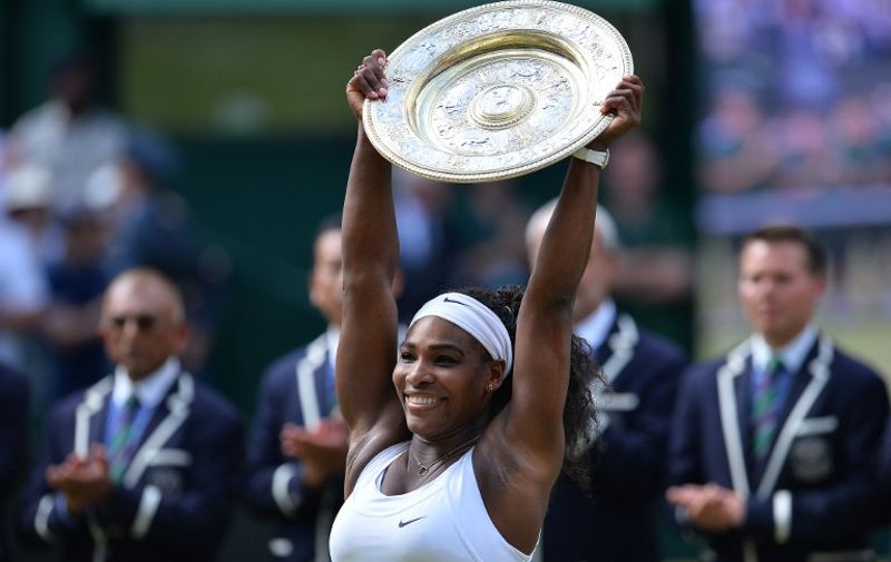 US player Serena Williams celebrates with the winner's trophy, the Venus Rosewater Dish, after her women's singles final victory over Spain's Garbine Muguruza on day twelve of the 2015 Wimbledon Championships at The All England Tennis Club in Wimbledon, southwest London, on July 11, 2015.   RESTRICTED TO EDITORIAL USE  --  AFP PHOTO / GLYN KIRK