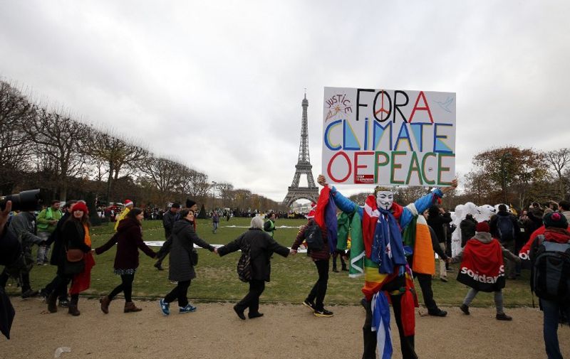 A demonstrator wearing a mask of the Anonymous group holds a banner reading "For a climate of Peace" during a rally called by several Non Governmental Organisations (NGO) to form a human chain on the Champs de Mars near the Eiffel Tower in Paris on December 12, 2015 on the sidelines of the COP21, the UN conference on global warming.
French hosts submit the final version of a global climate-saving pact to negotiators at UN Conference on december 12. The goal is for ministers to approve the agreement by the end of the day but that could be extended one more day. / AFP / FRANCOIS GUILLOT