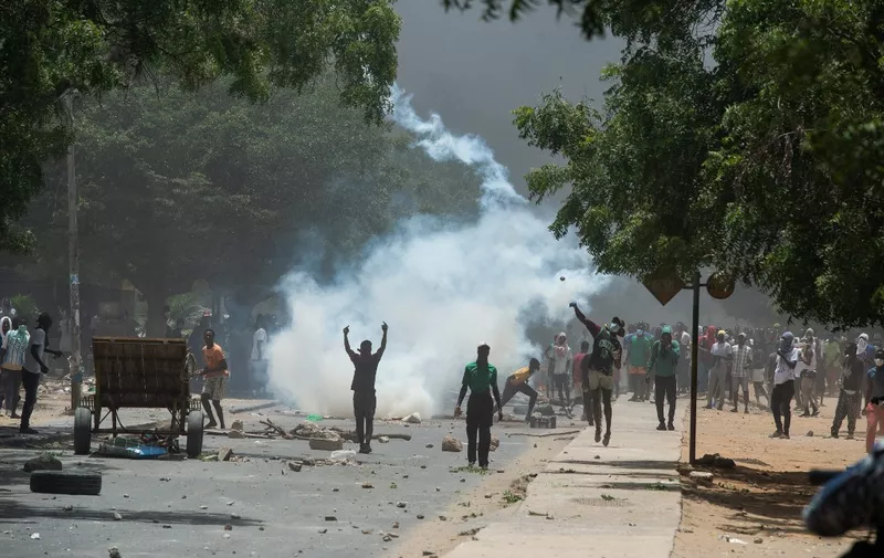 Supporters of opposition leader, Ousmane Sonko throw stones while police fire tear gas in Dakar on June 1, 2023, during unrest following the sentence of opponent Ousmane Sonko. A court in Senegal on Thursday sentenced opposition leader Ousmane Sonko, a candidate in the 2024 presidential election, to two years in prison on charges of "corrupting youth" but acquitted him of rape and issuing death threats. (Photo by GUY PETERSON / AFP)