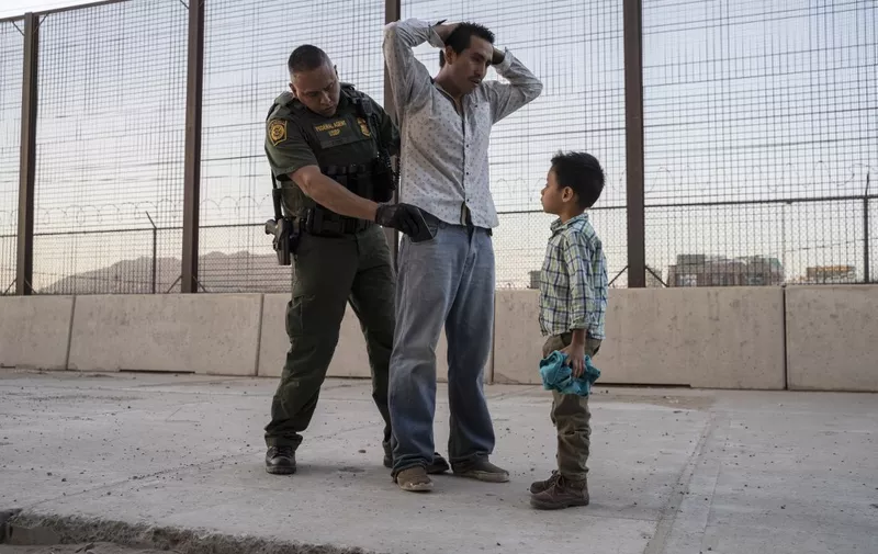 (FILES) In this file photo taken on May 16, 2019 Jose, 27, with his son José Daniel, 6, is searched by US Customs and Border Protection Agent Frank Pino, in El Paso, Texas. - The Trump administration moved July 15, 2019 to declare ineligible for asylum most migrants who cross the US southern border after passing through Mexico. A new rule redefining asylum eligibility -- to take effect on July 16, 2019 -- is the latest attempt to stem the flow of undocumented migrants into the country, and comes with the White House frustrated at Congress's failure to toughen immigration laws. (Photo by Paul Ratje / AFP)