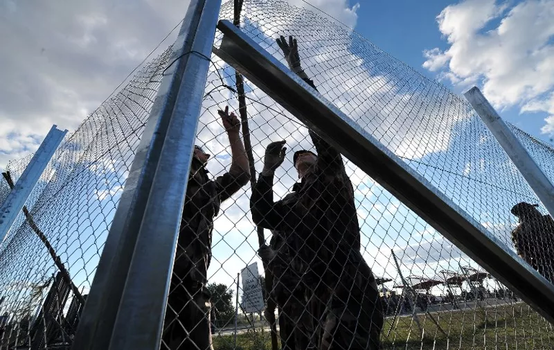 Hungarian soldiers raise a fence at the Croatian-Hungarian border between the villages of Baranjsko Petrovo Selo, Croatia and Beremend, Hungary on September 21, 2015. The fence system including chicken wire and barb-wire is in place at the border area to close the official border crossing in village of Beremend thus preventing further influx of Middle-Eastern migrants into Hungary. AFP PHOTO / ELVIS BARUKCIC