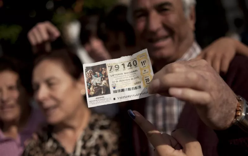 A group of people celebrate in a street of Villanueva de la Concepcion, near Malaga, as they hold a ticket wlth the first prize of the Spain's Christmas lottery named "El Gordo" (Fat One) on December 22, 2015. This year's winning number is 79140 representing takings of 4 million euros (£2.9 million). The Gordo lottery first took place in 1812 in Cadiz and has not missed a year since, continuing through Spains civil war between 1936 and 1939. In 1938, there were actually two Christmas lotteries, one held in Burgos by dictator General Francos Nationalist regime, and the other in Republican-ruled Barcelona.  AFP PHOTO / JORGE GUERRERO / AFP / Jorge Guerrero
