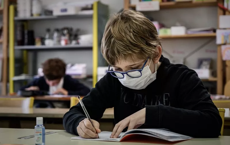 A pupil wearing a facemask attends a class at the private school Institut Sainte Genevieve in Paris on May 12, 2020, as the schools in France gradually reopen a day after a partial lifting of restrictions due to the Covid-19 pandemic caused by the novel coronavirus came into effect. (Photo by PHILIPPE LOPEZ / AFP)