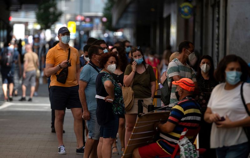 People wearing face masks queue to buy lottery tickets in the centre of Madrid on July 29, 2020. - Madrid moved to make mask-wearing obligatory at all times in public as Spain grappled with the fallout from a spike in virus cases that has triggered several international travel warnings. (Photo by PIERRE-PHILIPPE MARCOU / AFP)