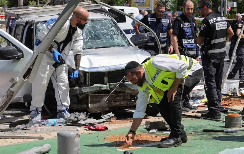 Members of Israeli security and emergency personnel work at the site of a reported car ramming attack in Tel Aviv on July 4, 2023. The suspected attack has resulted in injuries police and medics said, on the second day of a major Israeli army operation in the occupied West Bank. (Photo by JACK GUEZ / AFP)