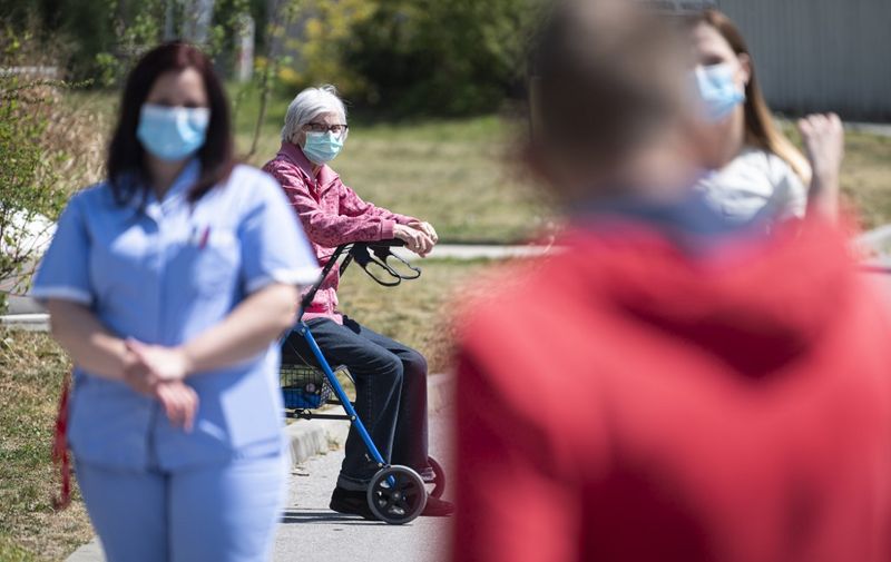 An elderly resident looks on as employees of the Domzale Elderly Care Home stage a fifteen-minute protest demanding from the government to improve their working conditions during the coronavirus epidemic on April 24, 2020 in Domzale, Slovenia. (Photo by Jure Makovec / AFP)