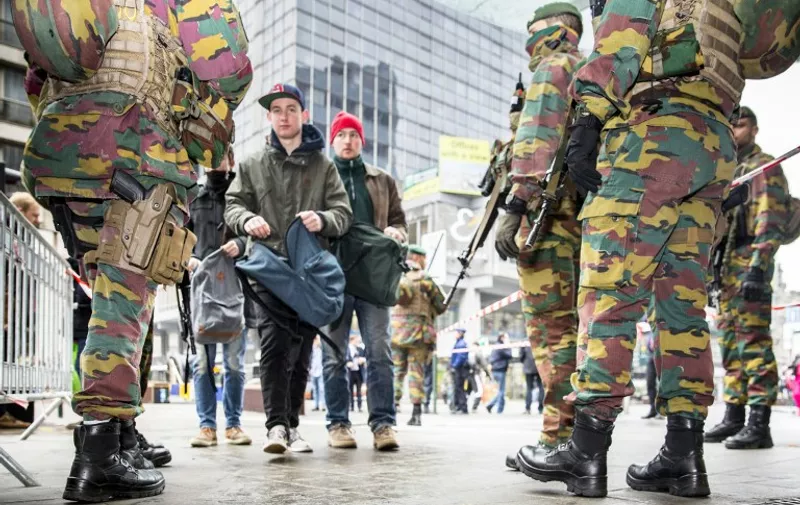 Soldiers control passers by in Brussels, on March 23 2016, one day after the attacks on Brussels airport and at a metro station. 
About 20 people were killed on the metro and 14 at the airport in the rush-hour assaults, which came just days after the arrest in Brussels of the main fugitive suspect in November's gun and bomb rampage in Paris.  / AFP / BELGA / HATIM KAGHAT / Belgium OUT