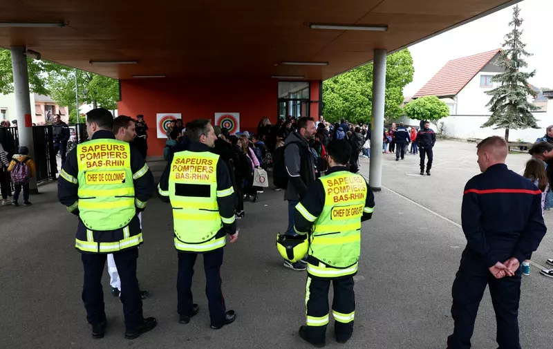 Parents collect their children with police forces and firefighter watching at a school in the eastern France city of Souffelweyersheim after two girls were wounded in a knife attack outside the school on April 18, 2024. (Photo by FREDERICK FLORIN / AFP)