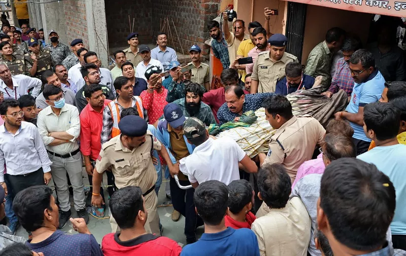 Rescue and security personnel carry a devotee on a stretcher who was injured after the floor covering a stepwell collapsed at a temple in Indore on March 30, 2023. - At least 13 devotees were killed and more than a dozen rescued on March 30 after they fell into a well at a Hindu temple in India, officials said. (Photo by AFP)