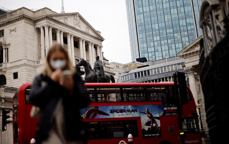 A pedestrian and a London bus go past the Bank of England in London on December 16, 2021. - The Bank of England hiked its key interest rate from 0.10 percent to 0.25 percent, as it seeks to combat decade-high inflation despite Omicron concerns. (Photo by Tolga Akmen / AFP)