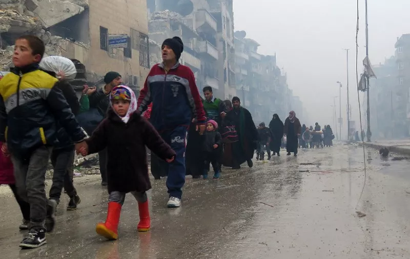 Syrian residents, fleeing violence in the restive Bustan al-Qasr neighbourhood, arrive in Aleppo's Fardos neighbourhood on December 13, 2016, after regime troops retook the area from rebel fighters. 
Syrian rebels withdrew from six more neighbourhoods in their one-time bastion of east Aleppo in the face of advancing government troops, the Syrian Observatory for Human Rights said. / AFP PHOTO / STRINGER