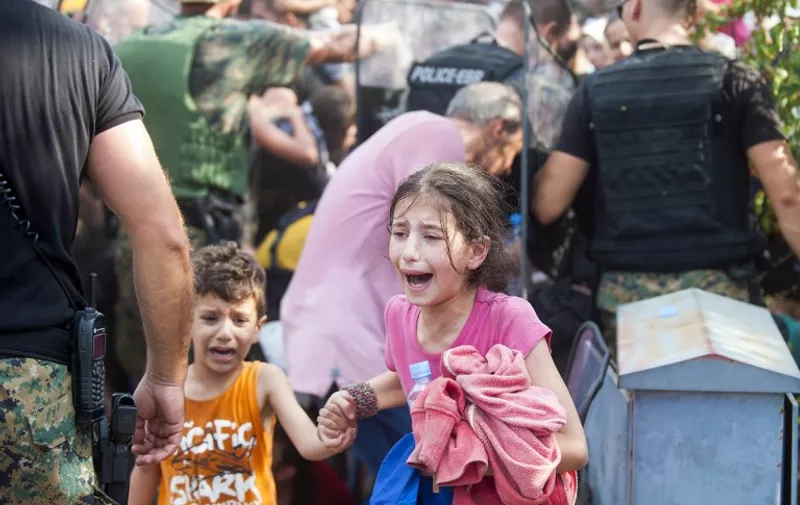 A young girl and boy cry as police block a group of migrants trying to cross the Macedonian-Greek border near the town of Gevgelija on August 21, 2015. Macedonia said on August 20 that it had declared a "state of emergency" on its southern border with Greece and would draft in the army to help control the influx of migrants crossing the frontier. AFP  PHOTO / ROBERT ATANASOVSKI