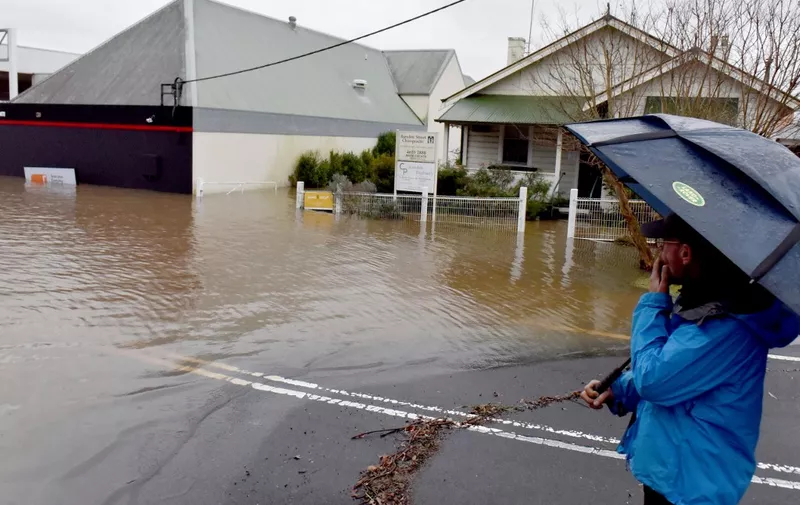 A man looks at a flooded residential area due to torrential rain in the Camden suburb of Sydney on July 3, 2022. - Thousands of Australians were ordered to evacuate their homes in Sydney on July 3 as torrential rain battered the country's largest city and floodwaters inundated its outskirts. (Photo by Muhammad FAROOQ / AFP)