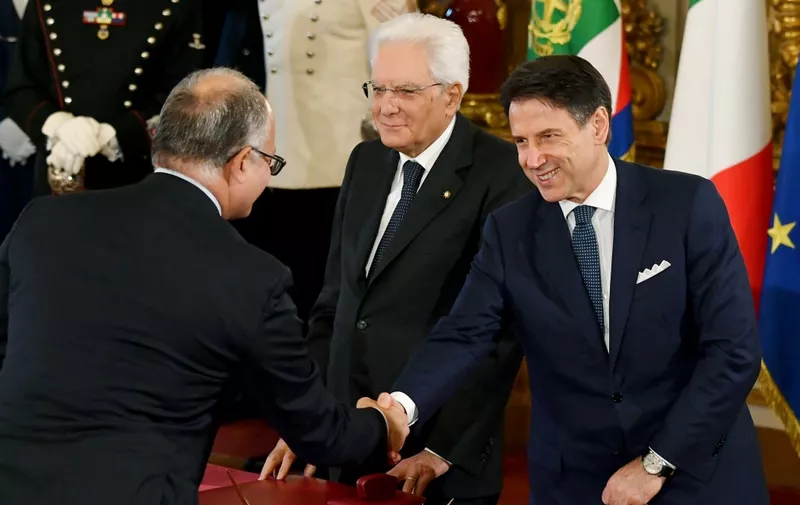 Italy's Finance and Economy Minister Roberto Gualtieri (L) shakes hand with Italy's Prime Minister Giuseppe Conte as Italy's President Sergio Mattarella (C) looks on after signing an oath of office during a swearing-in ceremony of the new Cabinet at the Quirinale presidential palace in Rome on September 5, 2019. - Prime Minister Giuseppe Conte on September 4 unveiled Italy's new government, a coalition of the anti-establishment Five Star Movement (M5S) and centre-left Democratic Party (PD). Conte, who remains at the helm after 14 months at the head of the outgoing populist government, presented 21 new ministers to be sworn in on September 5. (Photo by Andreas SOLARO / AFP)