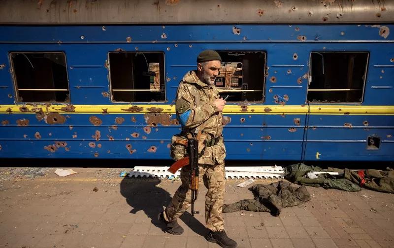 a Ukrainian serviceman walks near a damaged train in the northeastern city of Trostyanets', on March 29, 2022. - Ukraine said on March 26, 2022 its forces had recaptured the town of Trostyanets, near the Russian border, one of the first towns to fall under Moscow's control in its month-long invasion. (Photo by FADEL SENNA / AFP)