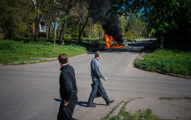 Local residents look at a car burning after a shelling in a street of Kostyantynivka, Donetsk region on May 3, 2023, amid the Russian invasion of Ukraine. (Photo by Dimitar DILKOFF / AFP)