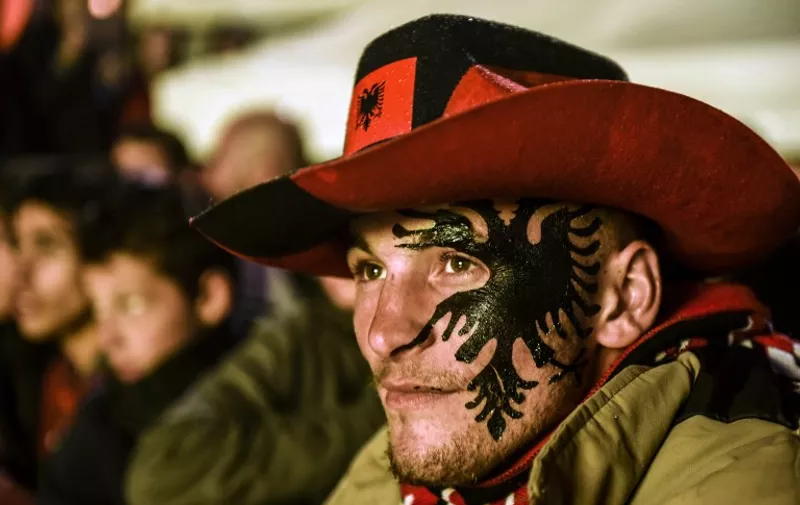 A fan with the arms of Kosovo painted on his face watches on a big screen in Pristina on October 8, 2015 a live broadcast of the Euro 2016 qualifying football match between Albania and Serbia played at the Elbasan Arena in Elbasan, Albania. AFP PHOTO / ARMEND NIMANI / AFP / ARMEND NIMANI