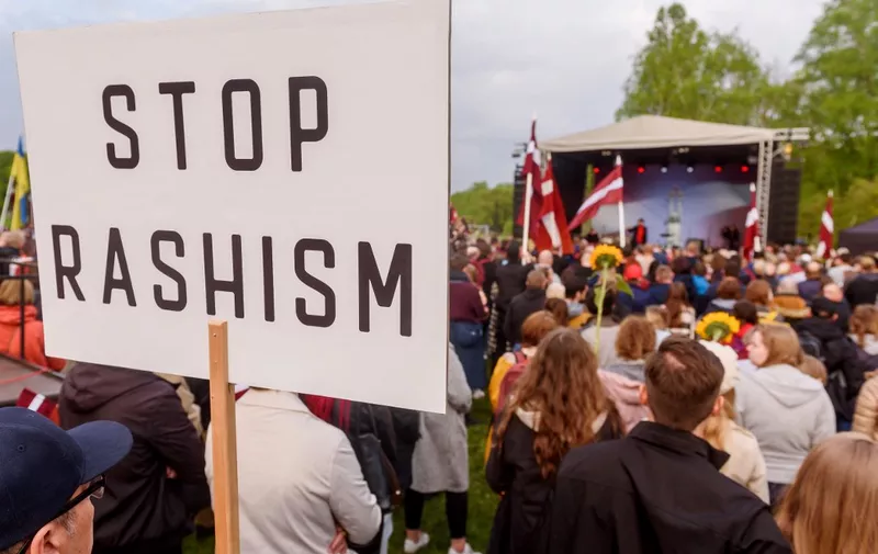 Participants of a rally "Getting Rid of Soviet Heritage" hold up a placard reading 'Stop Rashism' after marching from the Freedom Monument to the Soviet Victory Monument in Riga, Latvia on May 20, 2022. - Thousands rallied in Latvia on May 20 near a Soviet-era monument, which has become a rallying point for pro-Kremlin supporters in the Baltic state, to call for the World War II memorial to be destroyed. Protesters could be seen carrying placards reading "Support Ukrainians" and "Our land, Our rules" and waved Latvian and Ukrainian flags. Local media reported around 10,000 participants. (Photo by Gints Ivuskans / AFP)