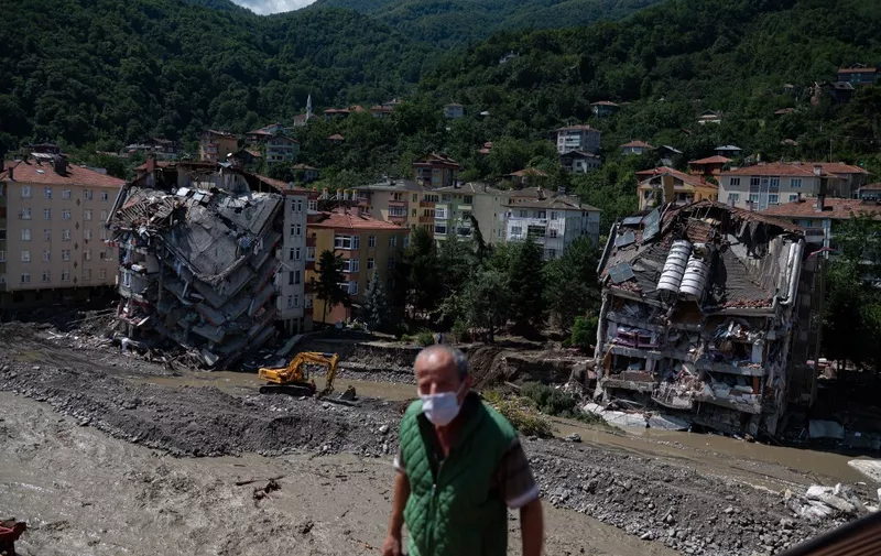 A digger works near two collapsed buildings following flash floods the day before in the town of Bozkurt in the district of Kastamonu, in the Black Sea region of Turkey on August 15, 2021. - Turkey battled disaster on two fronts with eight people dying when a fire-fighting aircraft crashed and rescuers racing to find survivors of flash floods in the north that have killed at least 55. (Photo by Yasin AKGUL / AFP)