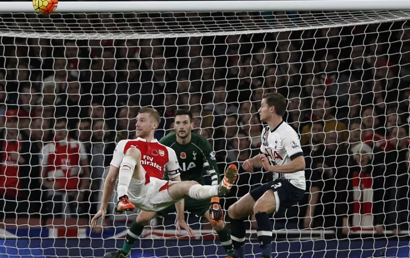 Arsenal's German defender Per Mertesacker (L) tries an overhead kick during the English Premier League football match between Arsenal and Tottenham Hotspur at the Emirates Stadium in London on November 8, 2015.     

RESTRICTED TO EDITORIAL USE. No use with unauthorized audio, video, data, fixture lists, club/league logos or 'live' services. Online in-match use limited to 75 images, no video emulation. No use in betting, games or single club/league/player publications.