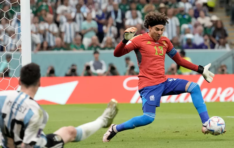 Argentina's Lionel Messi, left, falls to the ground as Mexico's goalkeeper Guillermo Ochoa makes a save during the World Cup group C soccer match between Argentina and Mexico, at the Lusail Stadium in Lusail, Qatar, Saturday, Nov. 26, 2022. (AP Photo/Moises Castillo)