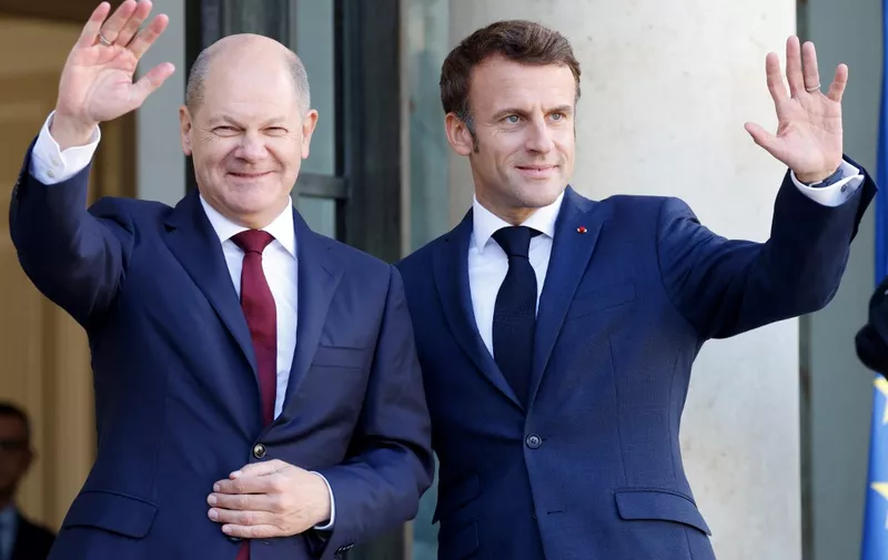 (FILES) In this file photo taken on October 26, 2022 France's President Emmanuel Macron (R) and German Chancellor Olaf Scholz wave upon Scholz' arrival for a lunch at the presidential Elysee Palace in Paris. - January 22, 2023 marks the 60th anniversary of the landmark treaty signed January 22, 1963 by then French president Charles de Gaulle and West German chancellor Konrad Adenauer, sealing a new era of reconciliation between the former foes, which has since driven European unity. (Photo by Ludovic MARIN / AFP)