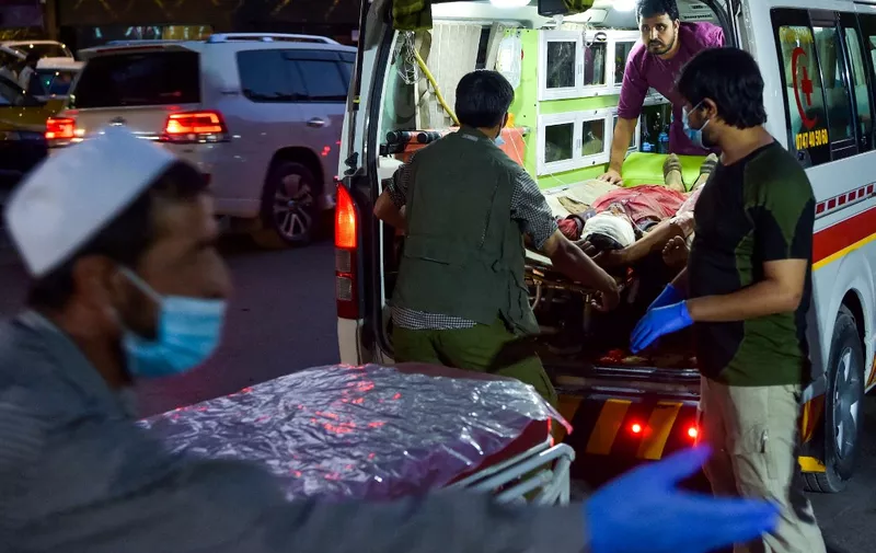 EDITORS NOTE: Graphic content / Medical staff bring an injured man to a hospital in an ambulance after two powerful explosions, which killed at least six people, outside the airport in Kabul on August 26, 2021. (Photo by Wakil KOHSAR / AFP)