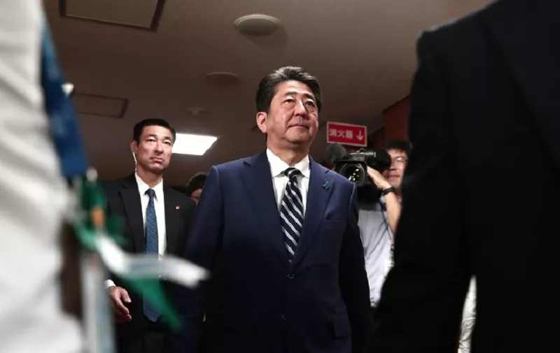 Japan's Prime Minister and ruling Liberal Democratic Party (LDP) leader Shinzo Abe (C) arrives at the party headquarters to put rosettes by successful general election candidates' names on a board in Tokyo on October 22, 2017.
Abe swept to a resounding victory in a snap election on October 22, winning a mandate to harden his already hawkish stance on North Korea and re-energise the world's number-three economy. / AFP PHOTO / Behrouz MEHRI