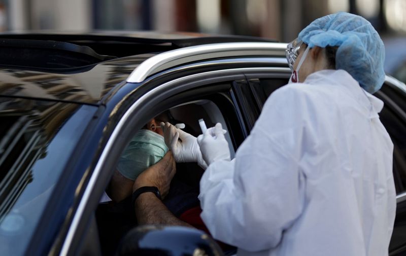 A biologist collects a sample from a man at a COVID-19 screening-drive, on April 22, 2020, in Neuilly-sur-Seine, near Paris, on the 37th day of a lockdown in France to stop the spread of the COVID-19 pandemic, caused by the novel coronavirus. (Photo by THOMAS COEX / AFP)