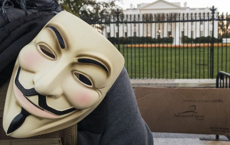 A protester stands with a Guy Fawkes mask stand near the White House during the Anonymous Million Mask March on the streets of downtown Washington, DC on November 5, 2015. The idea of "Million Mask March" is to get Anonymous protesters from all over the world to gather publicly on November 5.  AFP PHOTO/ PAUL J. RICHARDS