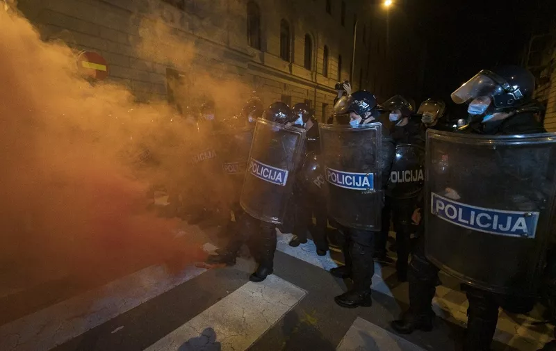 Anti-riot police officers kick a flare away during an anti-government protest in Ljubljana, Slovenia, on October 9, 2020. (Photo by Jure Makovec / AFP)