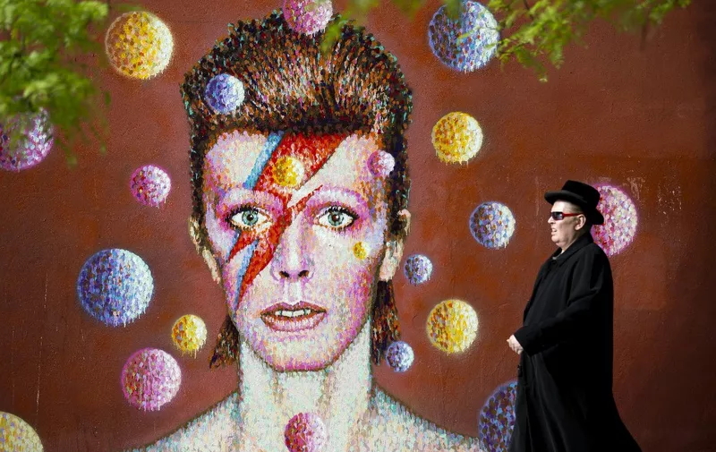 A man walks past a 3D wall portrait of British musician David Bowie, created by Australian street artist James Cochran, also known as Jimmy C, in Brixton, South London, on June 19, 2013. The artwork is based on the iconic cover for Bowies 1973 album, Aladdin Sane. AFP PHOTO/JUSTIN TALLIS (Photo by JUSTIN TALLIS / AFP)