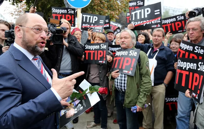 President of the European Parliament and Social democrate Martin Schulz (L) speaks with protestors during a demonstration against the Transatlantic Trade and Investment Partnership (TTIP) in front of the party headquarters of the Social Democrate Party in Berlin on September 20, 2014. Delegates of the Social Democrate Party meet also to find an agreement on the controversial treaty. AFP PHOTO / DPA/ WOLFGANG KUMM   GERMANY OUT