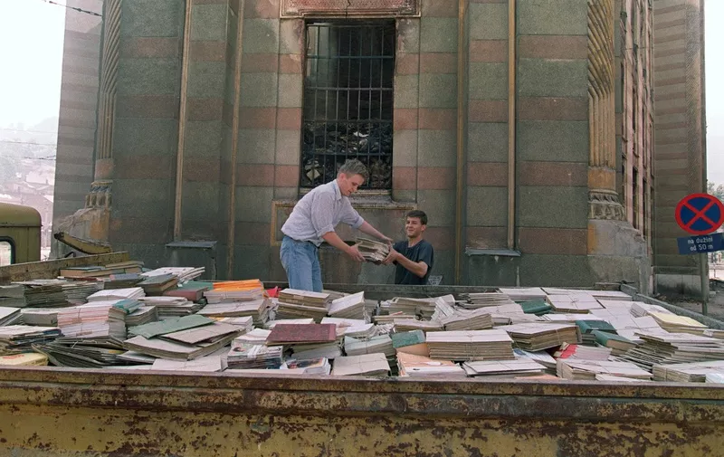 Sarajevo residents try to save some books from the basement of the National Library in Sarajevo on August 29, 1992. The Historical Library buiding of the Bosnian capital was partly destroyed and burned due to Serbian shelling. AFP PHOTO MANOOCHER DEGHATI (Photo by MANOOCHER DEGHATI / AFP)