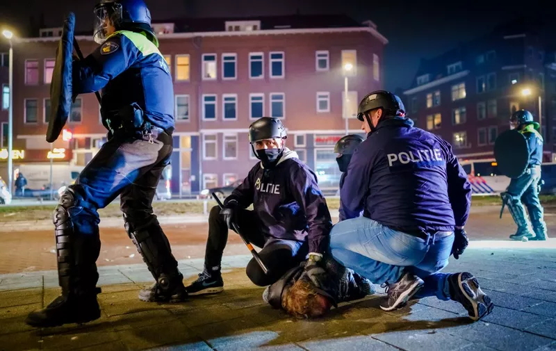 Dutch policemen arrest a man during clashes with a large group of young people on Beijerlandselaan in Rotterdam, on January 25, 2021. - The Netherlands was hit by a second wave of riots on January 25 evening after protesters again went on the rampage in several cities following the introduction of a coronavirus curfew over the weekend. Riot police clashed with groups of protesters in the port city of Rotterdam, where they used a water canon. (Photo by Marco de Swart / ANP / AFP) / Netherlands OUT