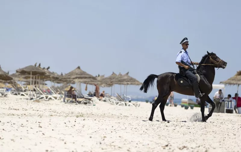 A Tunisian policeman patrols the beach in front of the Riu Imperial Marhaba Hotel in Port el Kantaoui, on the outskirts of Sousse south of the capital Tunis, on June 28, 2015, following a shooting attack two days earlier. In April, tourism saw a 25.7 percent drop in the number of visitors on the same month in 2014 and a 26.3 percent fall in revenues, according to the Tunisian central bank. AFP PHOTO / KENZO TRIBOUILLARD