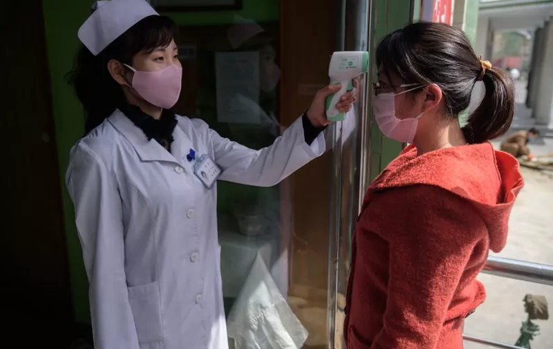 A health worker takes the temperature of a woman amid concerns over the COVID-19 coronavirus, at an entrance of the Pyongchon District People's Hospital in Pyongyang on April 1, 2020. (Photo by KIM Won Jin / AFP)