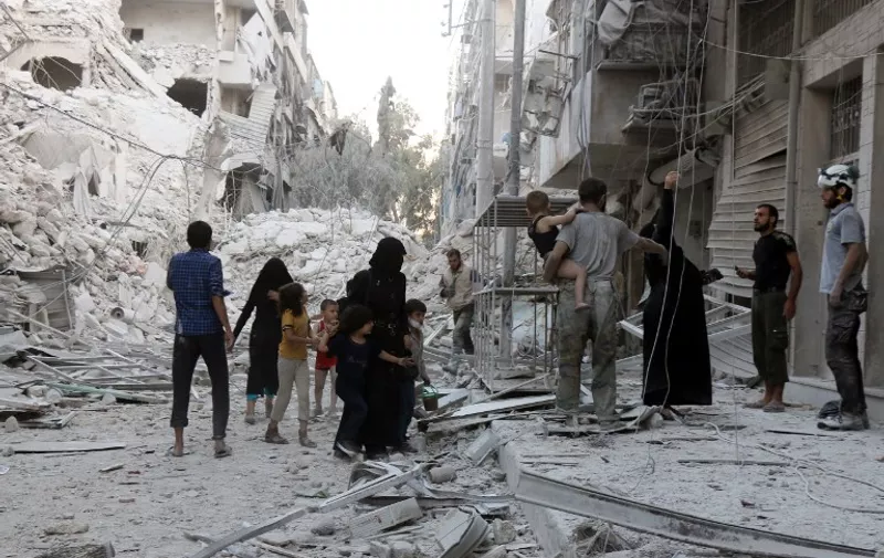 A Syrian family leaves the area following a reported airstrike on September 23, 2016, on the al-Muasalat area in the northern Syrian city of Aleppo.
Missiles rained down on rebel-held areas of Syria's Aleppo, causing widespread destruction that overwhelmed rescue teams, as the army prepared a ground offensive to retake the city. / AFP PHOTO / THAER MOHAMMED