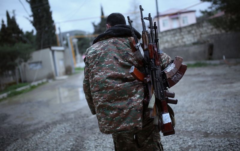 A soldier of the self-defense army of Nagorno-Karabakh carries weapons in Martakert region on April 4, 2016. - Fighting raged between Azerbaijani and Armenian forces overnight in the disputed Nagorny Karabakh region as international mediators are to meet on April 5 in Vienna in a bid to quench the worst violence in decades in the rebel territory. (Photo by Vahan Stepanyan / PAN Photo / AFP)