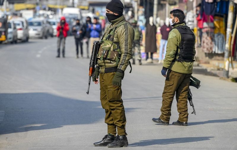 Policemen stand guard near a site where bomb disposal squad members work to defuse a grenade found in a cooker beside a street in Srinagar on January 14, 2022. (Photo by Tauseef MUSTAFA / AFP)
