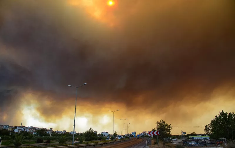 Heavy clouds of smoke rise from a massive forest fire which  engulfed a Mediterranean resort region on Turkey's southern coast near the town of Manavgat, on July 29, 2021. - At least three people were reported dead on July 29, 2021 and more than 100 injured as firefighters battled blazes engulfing a Mediterranean resort region on Turkey's southern coast. Officials also launched an investigation into suspicions that the fires that broke out Wednesday in four locations to the east of the tourist hotspot Antalya were the result of arson. (Photo by Ilyas AKENGIN / AFP)