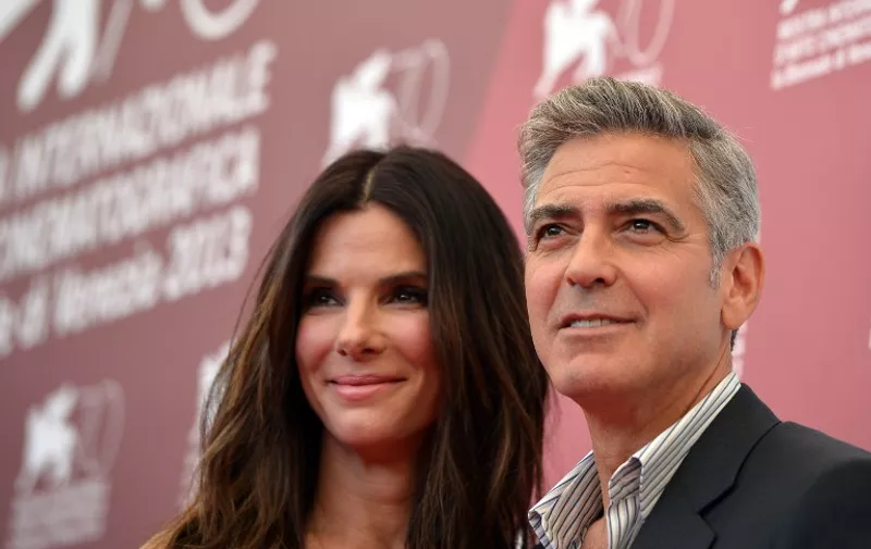 US actor George Clooney and US actress Sandra Bullock pose during the photocall of the movie "Gravity" presented out of competition on the opening day of the 70th Venice Film Festival on August 28, 2013 at Venice Lido. The Venice film festival kicks off today with the arrival of movie stars on water taxis for a dark line-up flush with fiendish tales of abuse, betrayal and survival. The world's oldest film festival opens with "Gravity", a 3-D sci-fi thriller starring George Clooney and Sandra Bullock as astronauts who are flung into deep space when a debris shower destroys their shuttle.  AFP PHOTO / GABRIEL BOUYS