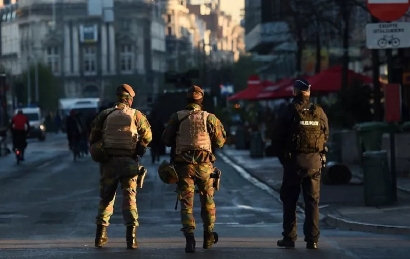 Two Belgian soldiers and a policeman patrol in Brussels on November 23, 2015 as the Belgian capital remains on the highest possible alert level. Brussels began a third consecutive day in lockdown under a maximum terror alert after Belgian police staged a series of raids but failed to find a key Paris attacks suspect. (Photo by EMMANUEL DUNAND / AFP)