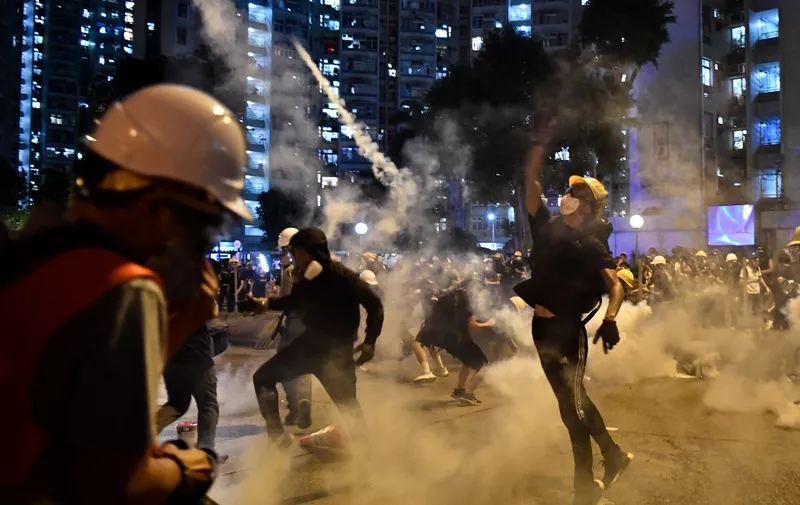 Protesters throw back tear gas fired by the police in Wong Tai Sin during a general strike in Hong Kong on August 5, 2019, as simultaneous rallies were held across seven districts. - Hong Kong riot police clashed with pro-democracy protesters for a third straight day on August 5 as the city's leader warned the global financial hub was nearing a "very dangerous situation", and a rare strike caused transport chaos. (Photo by Anthony WALLACE / AFP)