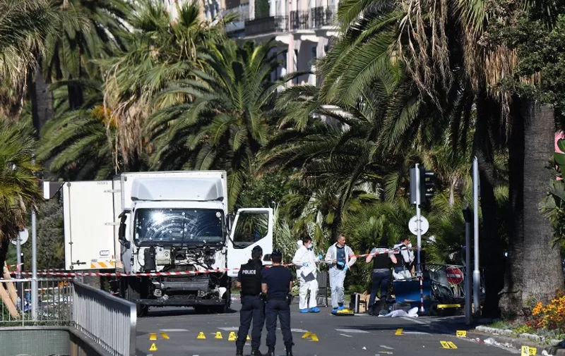 Forensics officers and policemen look for evidences near a truck on the Promenade des Anglais seafront in the French Riviera town of Nice on July 15, 2016, after it drove into a crowd watching a fireworks display.
An attack in Nice where a man rammed a truck into a crowd of people left 84 dead and another 18 in a "critical condition", interior ministry spokesman Pierre-Henry Brandet said Friday. An unidentified gunman barrelled the truck two kilometres (1.3 miles) through a crowd that had been enjoying a fireworks display for France's national day before being shot dead by police.
 / AFP PHOTO / ANNE-CHRISTINE POUJOULAT